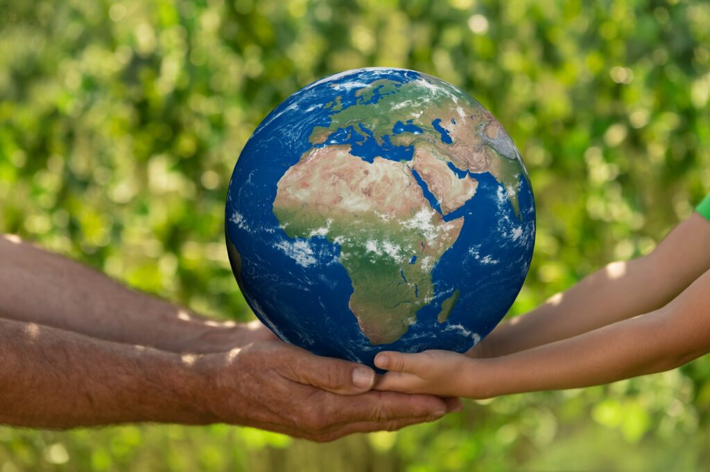 Senior man and child holding Earth planet. Elements of this image furnished by NASA